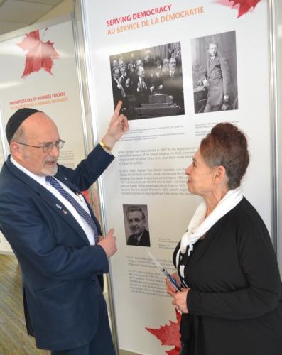 Rabbi Reuven Bulka and Sharon Gray - Shlozberg at the opening of the CJE Exhibition showing the CJE Serving Democracy panel. Rabbi Bulka is pointing to a photo of the Late Rt. Hon. Herb Gray flanked by Prime Ministers Jean Chretien and  PaulMartin in House of Commons. Other photos show Henry Nathan the first Jew elected to the Canadian House of Commons in 1871.  Below is David Lewis the first Jewish leader of a Canadian political party, the New Democratic Party.